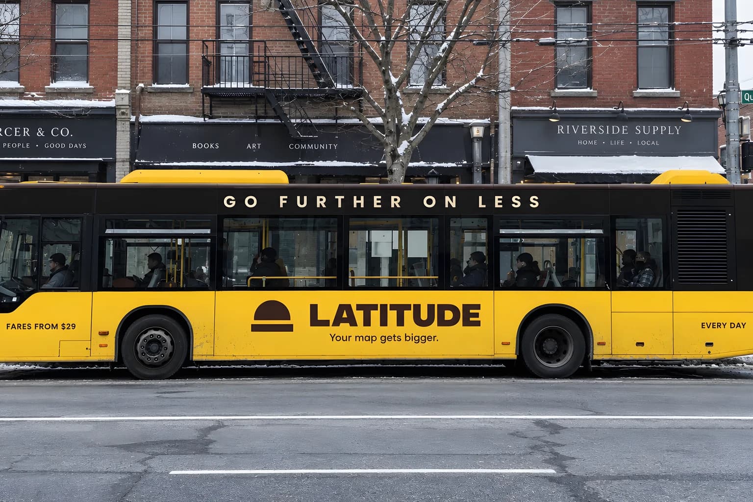 A city bus on a snowy street, its lower body golden yellow and its window band dark cocoa, carrying the Latitude wordmark with a half-dome mark, the line Your map gets bigger, and the words Go further on less above the windows.