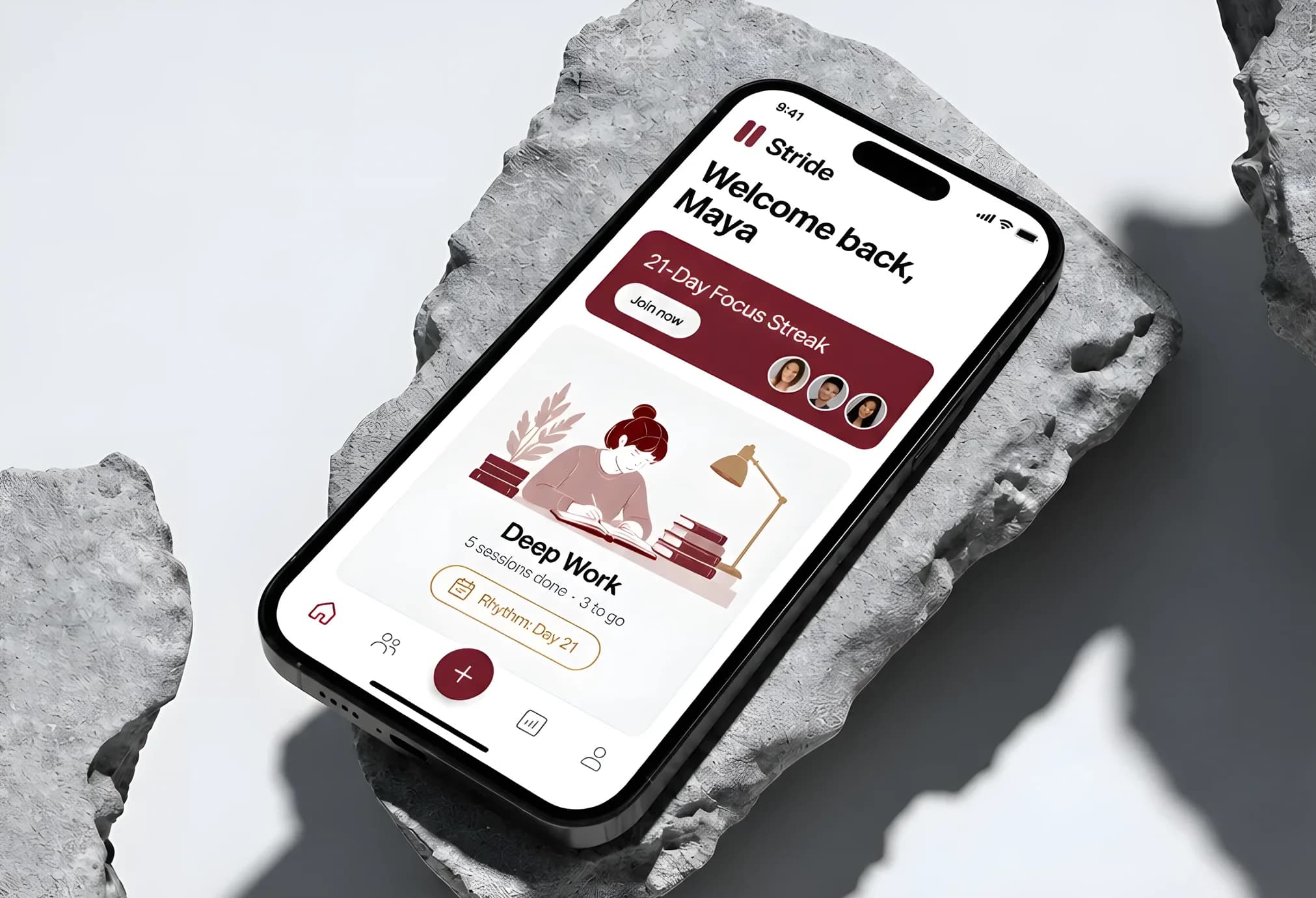 A phone resting on rough grey stone in hard daylight, showing the Stride home screen: Welcome back, Maya, a dark red 21-Day Focus Streak card and a Deep Work session.